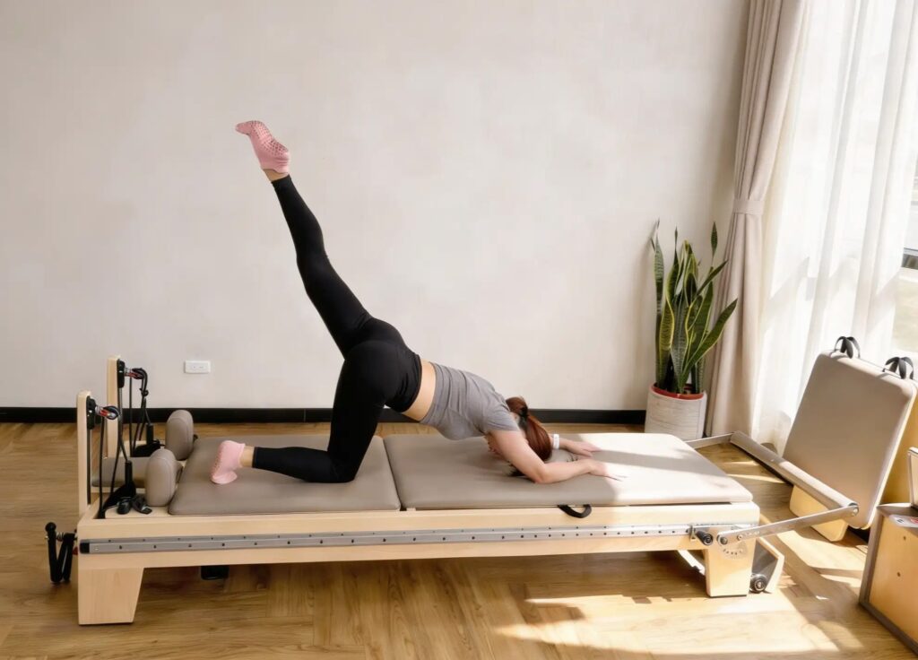 Một bộ ghế tập Reformer bằng nhôm kiểu full-rail kèm tháp nửa cao và một bộ ghế tập Reformer bằng gỗ phong với lớp bọc đồng bộ trong cùng một phòng tập